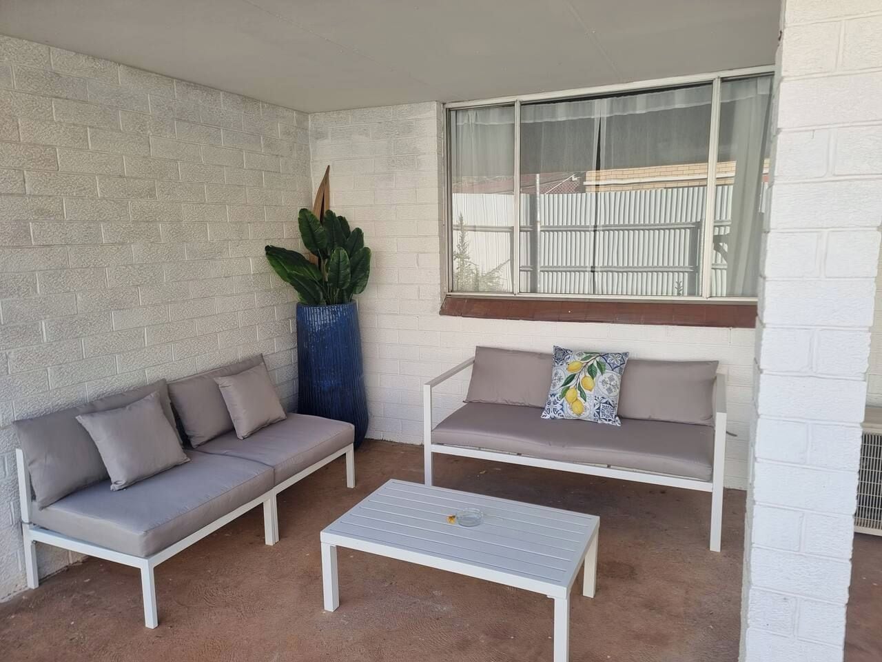 A patio area with two white sofas, a coffee table, and a large potted plant.