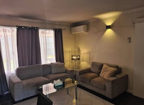 Ein Wohnzimmer mit einer Couch, einem Glastisch und einer Lampe.