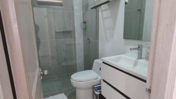Une salle de bain avec des toilettes, un lavabo et une douche.