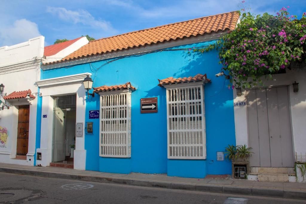 Un edificio con fachada azul, marcos de ventana blancos y techo de tejas.
