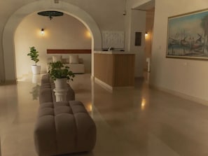 A modern interior with a sofa, a potted plant, and a reception desk. - Casa Villa Colonial By Akel Hotels (Cartagena de Indias)