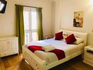 A hotel room with a bed, a nightstand, a television, and a painting on the wall. - Casa Villa Colonial By Akel Hotels (Cartagena de Indias)