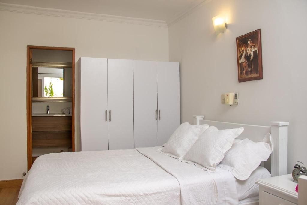 Un dormitorio con cama, armario blanco y un cuadro en la pared.