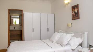 Un dormitorio con cama, armario blanco y un cuadro en la pared.