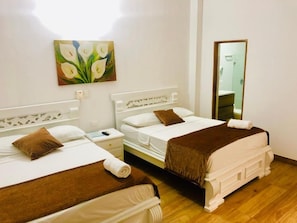 A hotel room with two beds, a painting on the wall, a mirror, and a wooden floor. - Casa Villa Colonial By Akel Hotels (Cartagena de Indias)