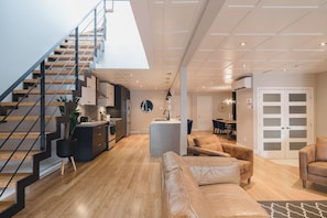 Un espace de vie moderne comprenant un escalier, une cuisine, un coin repas et un salon avec des canapés en cuir.