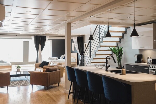 Une cuisine moderne dotée d’un îlot central, de tabourets de bar et d’un escalier menant à un niveau supérieur.