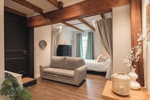 A room with a sofa, a bed, a wooden ceiling, a black door, and a plant. - Limoilou | 3 Bedrooms | Terrace | The 703 (Québec City)