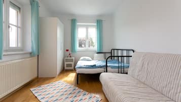 A bedroom with a bed, a nightstand, a window, and a radiator.