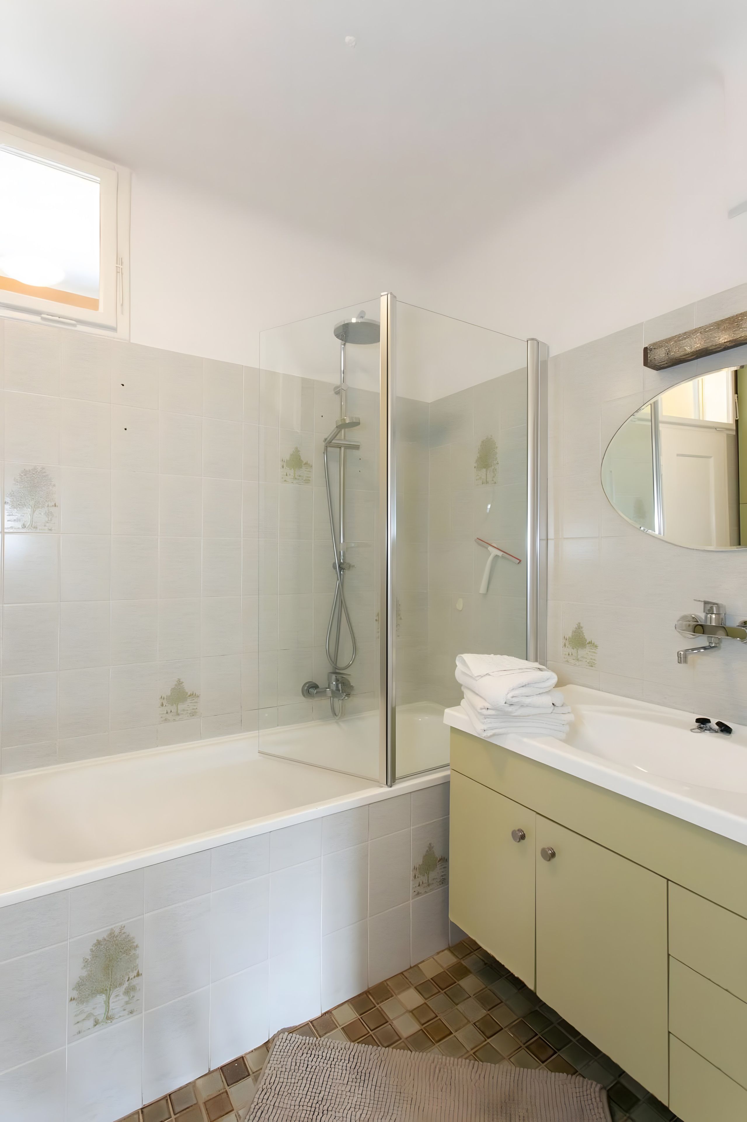 A modern bathroom with a glass-enclosed shower, a white bathtub, and a vanity with a mirror.