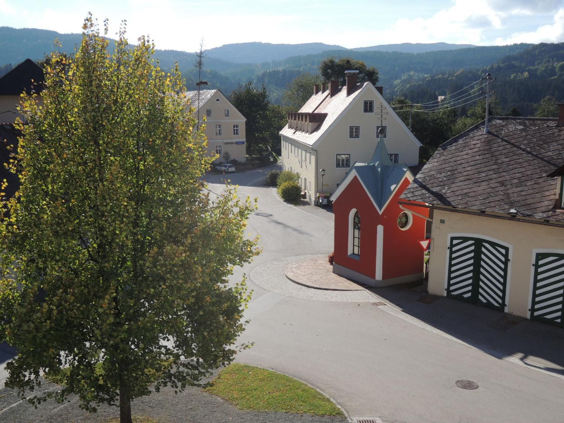 A residential street with houses, a tree, and a view of hills in the background.