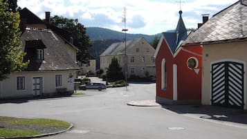 A quiet street with traditional buildings, a church steeple, and a car parked on the side.