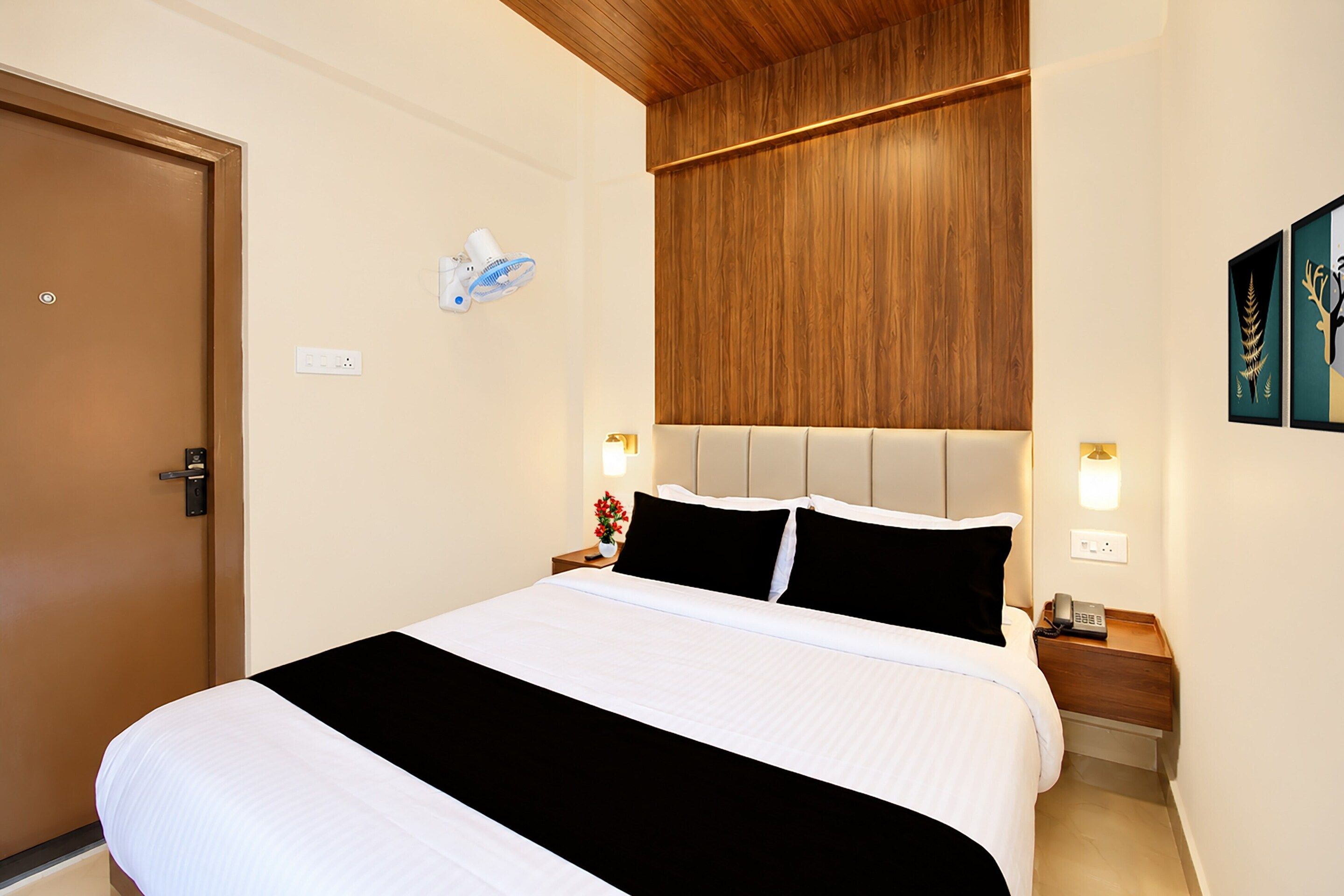 Una habitación de hotel con cama, techo de madera, lámpara de pared e imagen enmarcada.