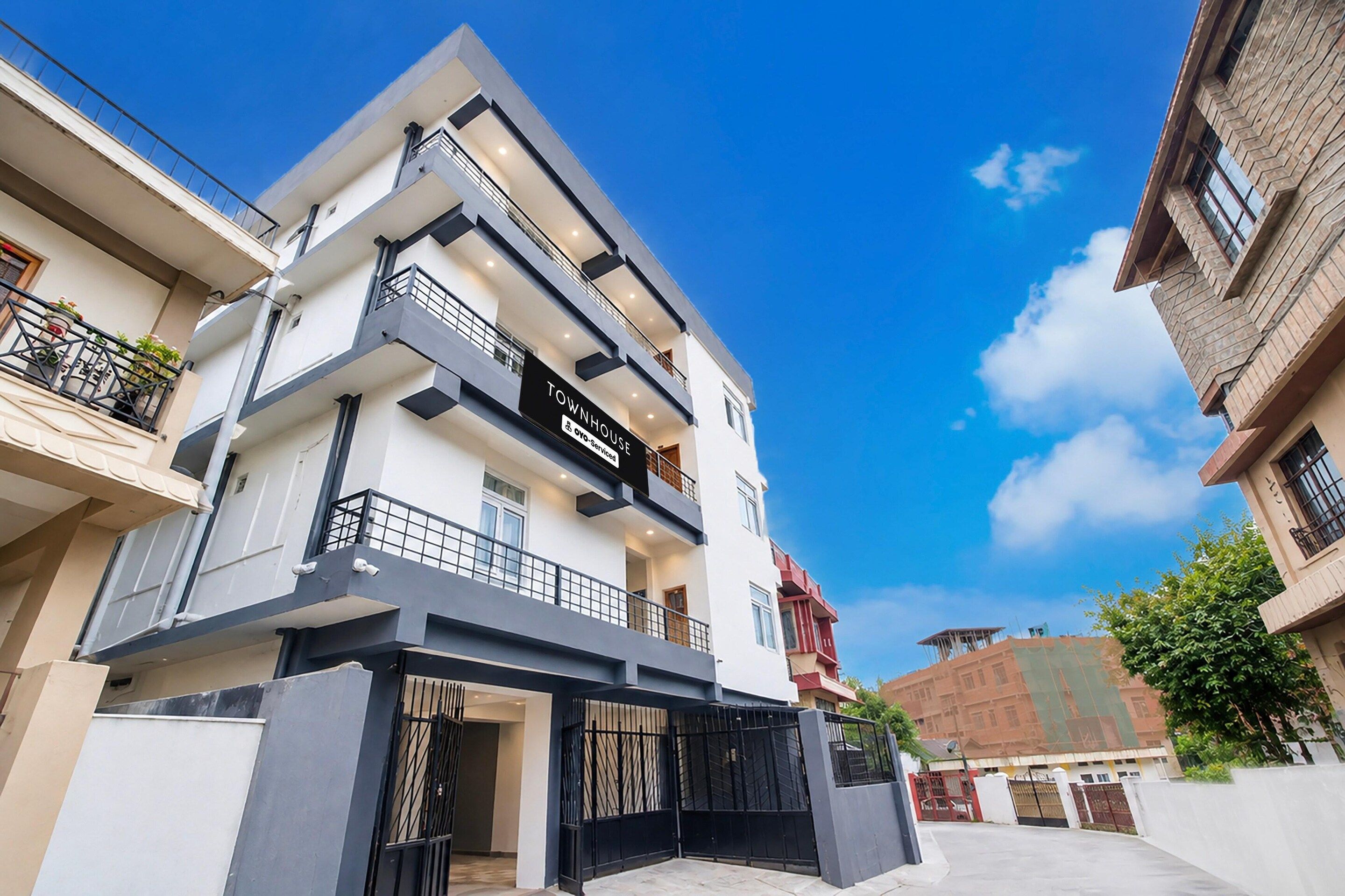 A multi-story residential building with a prominent 'TOWNHOUSE' sign, balconies, and a gated entrance.