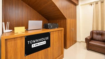 Una mesa de recepción con una computadora portátil, una impresora y un cartel que indica 'TOWNHOUSE & OYO-Serviced'.