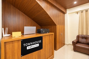 Una mesa de recepción con una computadora portátil, una impresora y un cartel que indica 'TOWNHOUSE & OYO-Serviced'.