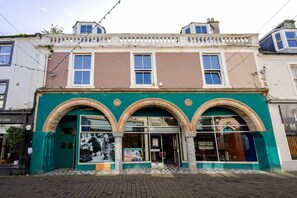 Edifício com fachada verde, entrada em arco e várias janelas.