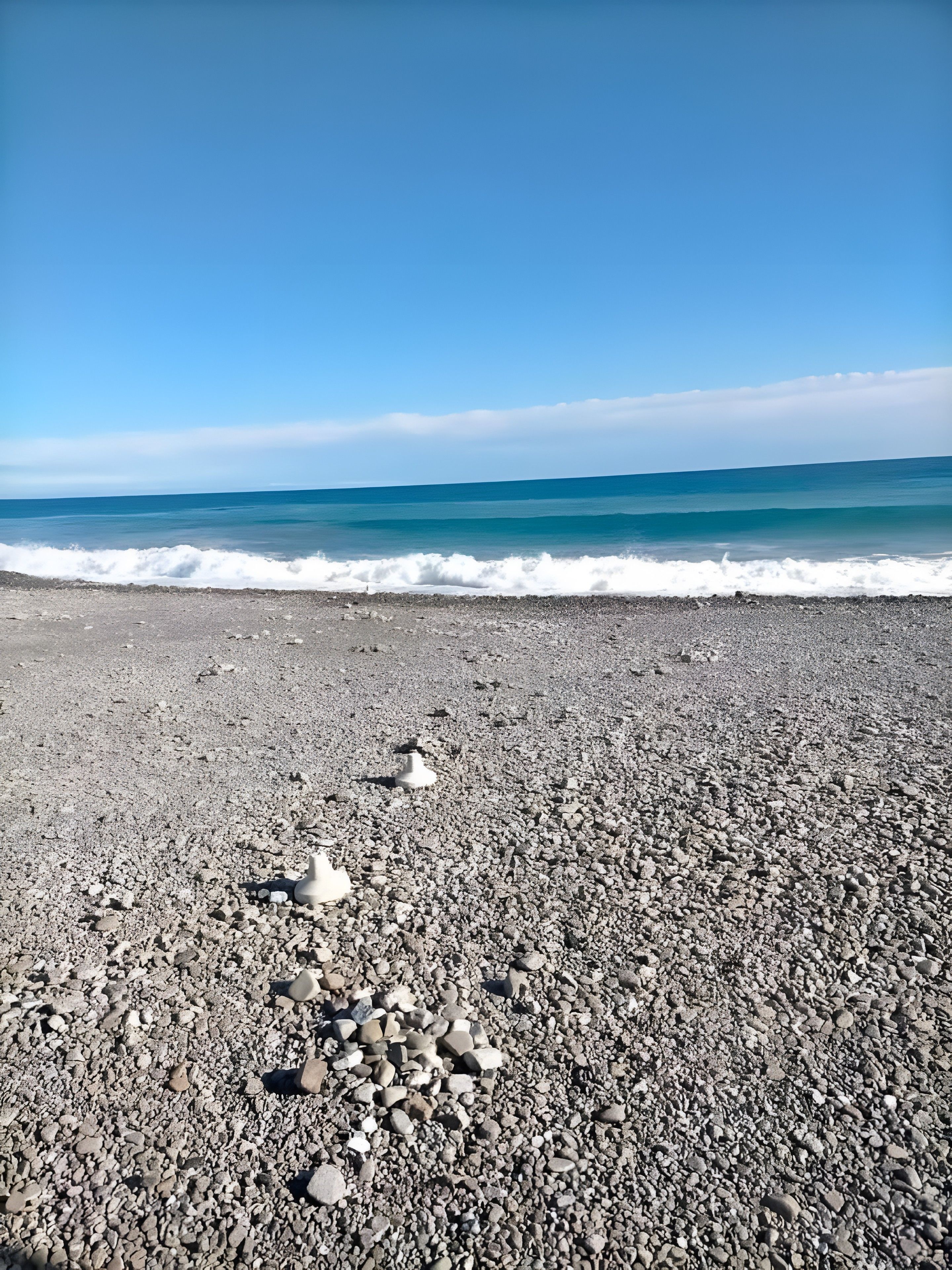 A pebbled beach with waves approaching the shore.