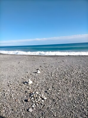 A pebbled beach with waves approaching the shore.