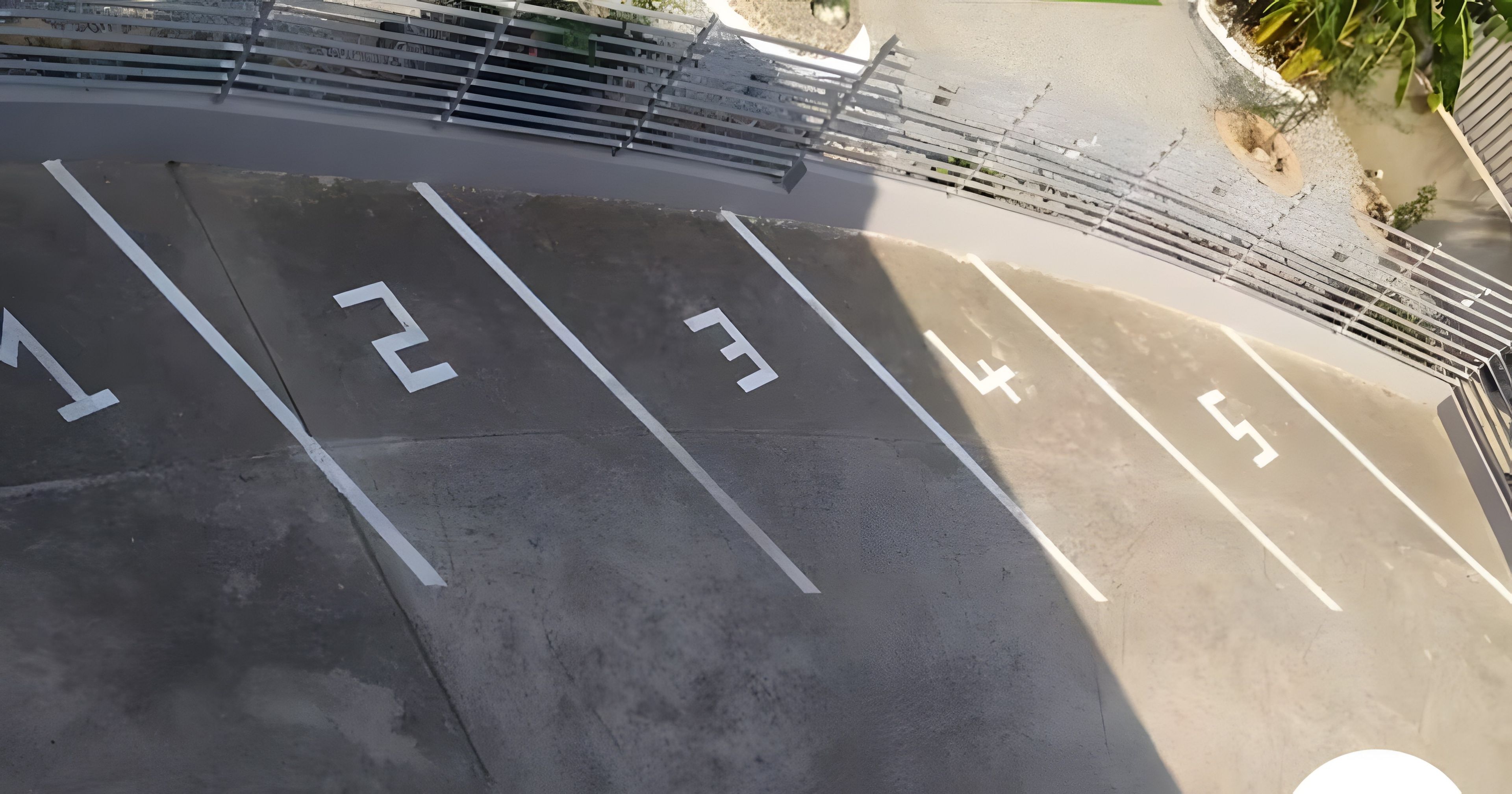 A parking area with numbered spaces and a metal fence.