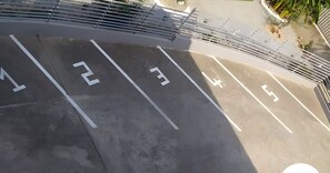 Un área de estacionamiento con espacios numerados y una cerca metálica.