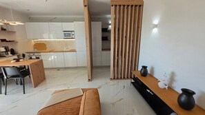 Eine moderne Küche mit weißen Schränken, einem Holztisch und einem schwarzen Sofa.