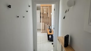A hallway with a wooden partition, a white door, and a shelf with a vase and a speaker. - Modern Apartment with Ocean View Near Downtown in a Hotel Complex (Albufeira)