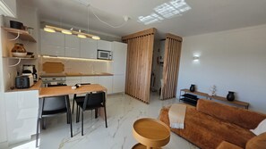 A compact living space with a kitchenette, dining area, and seating area. - Modern Apartment with Ocean View Near Downtown in a Hotel Complex (Albufeira)
