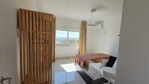 A bedroom with a bed, a window with a view, a wardrobe, and a ceiling fan. - Modern Apartment with Ocean View Near Downtown in a Hotel Complex (Albufeira)