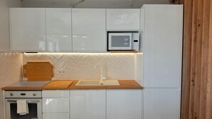 A kitchen with white cabinets, a wooden countertop, a built-in microwave, and an oven. - Modern Apartment with Ocean View Near Downtown in a Hotel Complex (Albufeira)