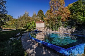 A clear swimming pool with a stone wall and a small building in the background. - 3 Bedroom Apartment TI&JAZ (Brežice)