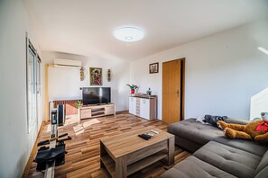 Ein modernes Wohnzimmer mit Flachbildfernseher, Holzböden, einer Couch und einem Couchtisch.