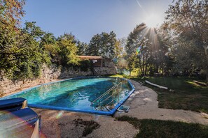 Ein Swimmingpool mit einer Steinmauer und einem Holzgebäude im Hintergrund.