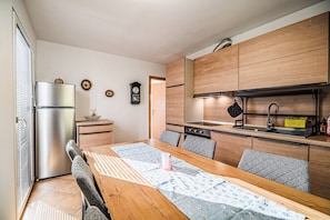 Une cuisine moderne avec des meubles en bois, un réfrigérateur en acier inoxydable et un coin repas comprenant une table et des chaises.