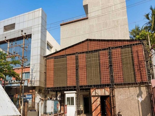 A building with a modern facade, a visible entrance, and a covered area with a metal roof. - Classic Hotel Sika Inn (Puducherry)