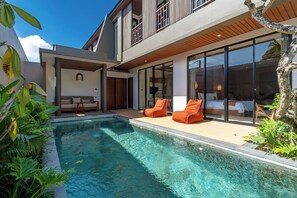 Ein modernes Haus mit Schwimmbad, Sitzgelegenheiten im Freien und großen Fenstern.