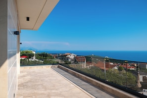 Un balcon offrant une vue dégagée sur la mer et les bâtiments environnants.