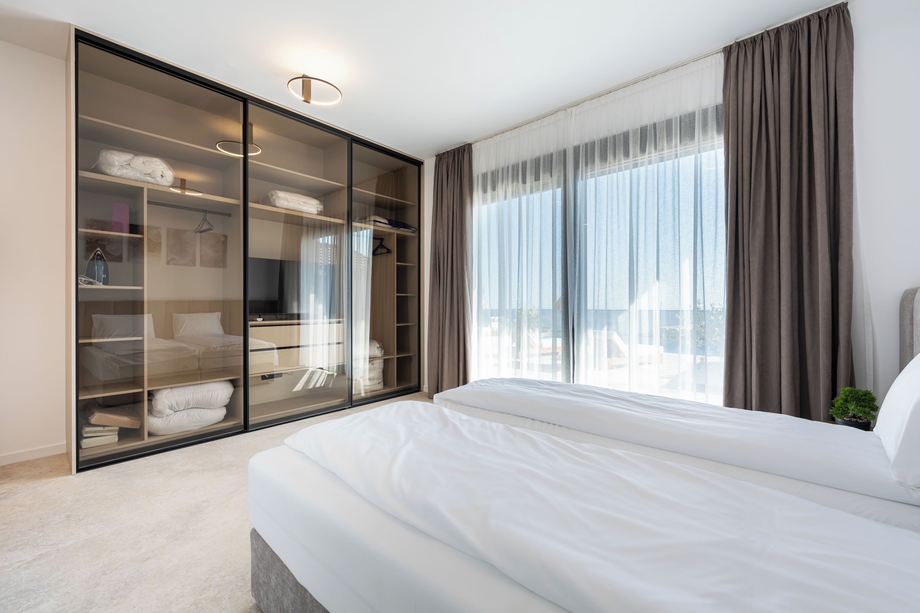 Een hotelkamer met een groot bed, een inloopkast en uitzicht op het omliggende landschap.