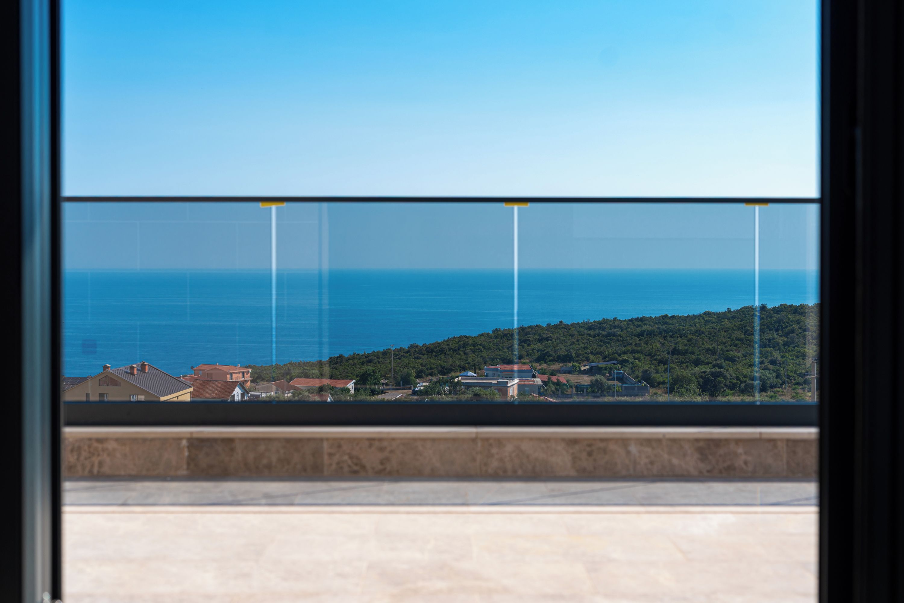 Ein Balkon mit freiem Blick auf das Meer und eine hügelige Landschaft.