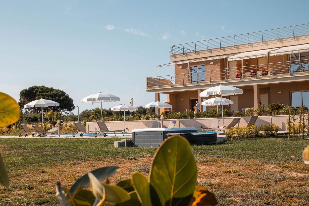 Un hotel moderno con zona de piscina, mobiliario exterior y un edificio de dos plantas.