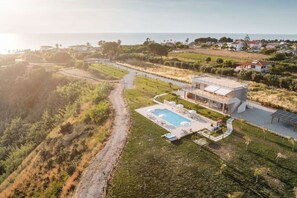 Une villa moderne dotée d’une piscine, entourée d’un jardin aménagé et offrant une vue sur la mer.