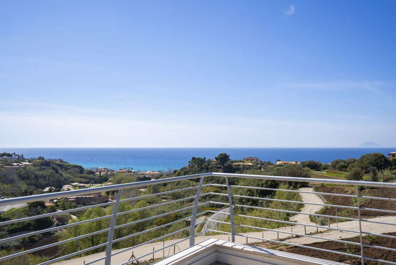 Ein Balkon mit Blick auf das Meer und ein fernes Gebirge.