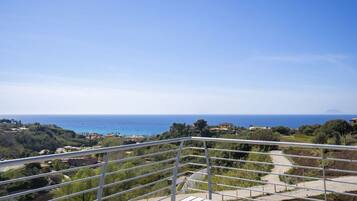 Ein Balkon mit Blick auf das Meer und ein fernes Gebirge.