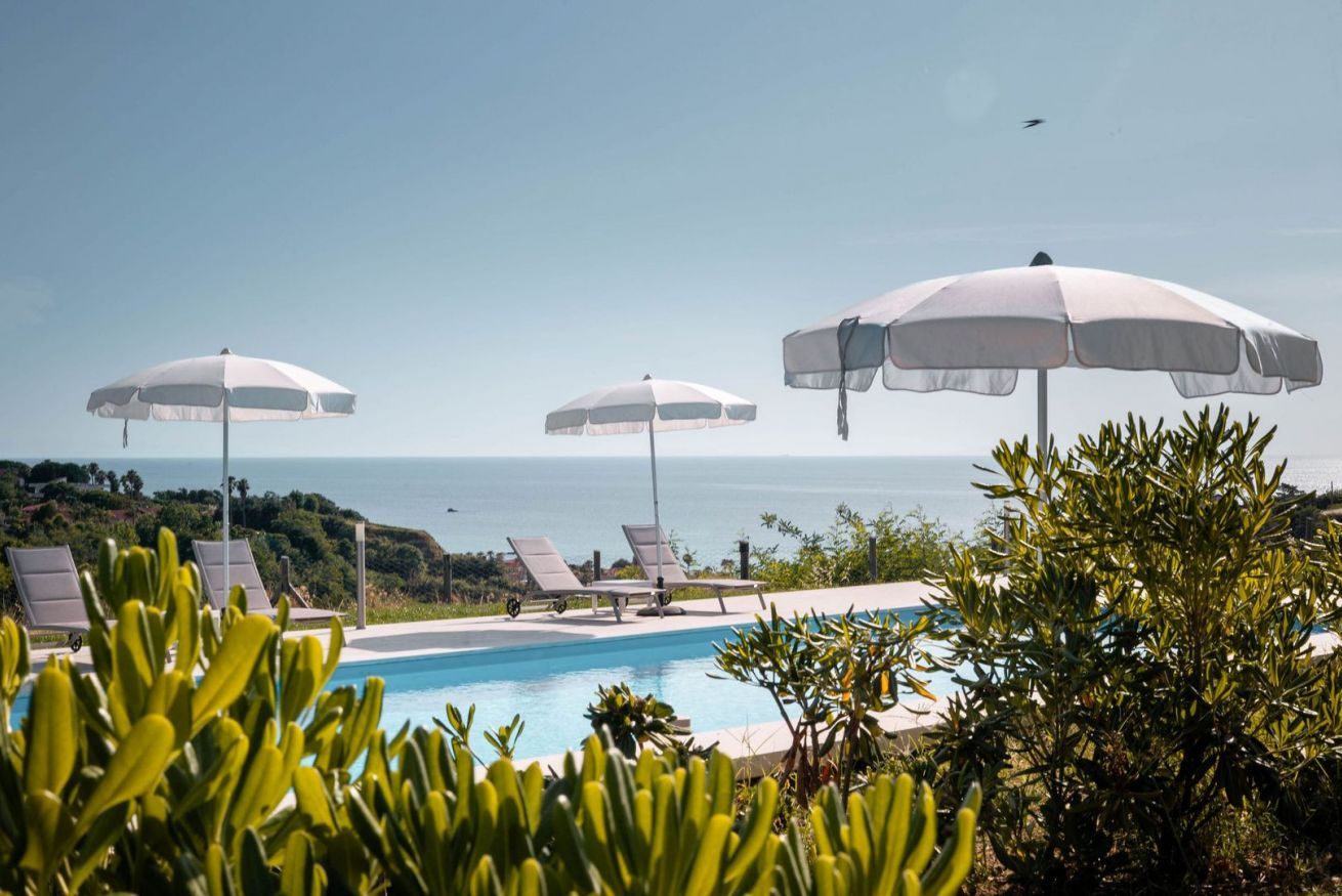 A poolside area with lounge chairs and umbrellas, overlooking a body of water.