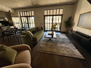 Ein modernes Wohnzimmer mit einer Couch, einem Esstisch und einer Küche im Hintergrund.