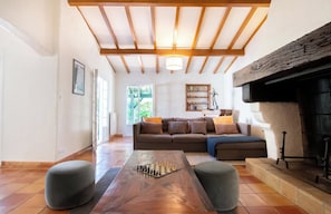 A spacious living room with a wooden ceiling, a fireplace, a sofa, and a chess table. - Villa des Landes - familiale - Seignosse (Seignosse)