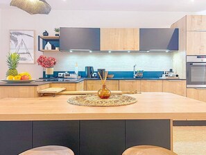 Cozinha moderna com ilha central, eletrodomésticos embutidos e uma janela ampla.