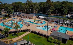 A large outdoor swimming pool area with multiple pools and a water slide. - Direct Oceanfront! Charming condo in Myrtle Beach perfect for your getaway! (Myrtle Beach)