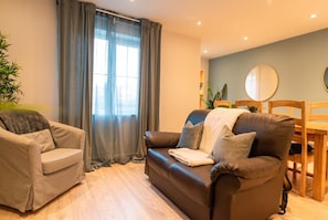 A living room with a brown leather sofa, a beige armchair, and a dining table with chairs. - Ground-Floor 2-Bed Sleeps 4 · Parking · Walk to Cardiff Bay (Cardiff)