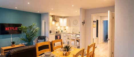A modern kitchen with white cabinets and a dining area with a wooden table set for four.